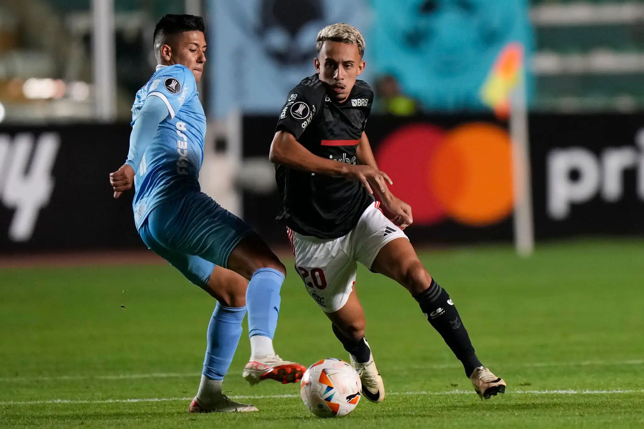 Ramiro Vaca, do Bolívar da Bolívia, à esquerda, e Matheus Gonçalves, do Flamengo do Brasil, disputam a bola durante uma partida de futebol