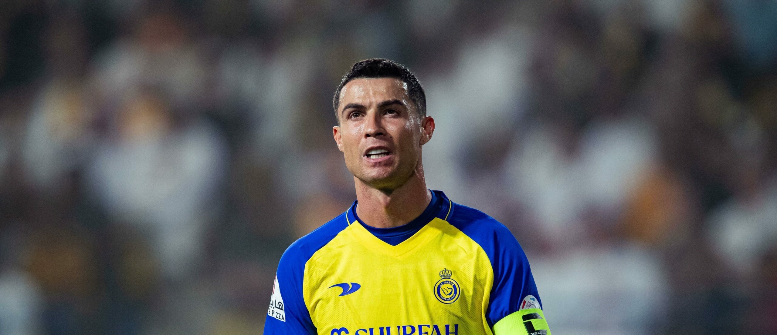 Cristiano Ronaldo, em campo, vestindo o uniforme amarelo e azul do Al Nassr, durante uma partida de futebol.
