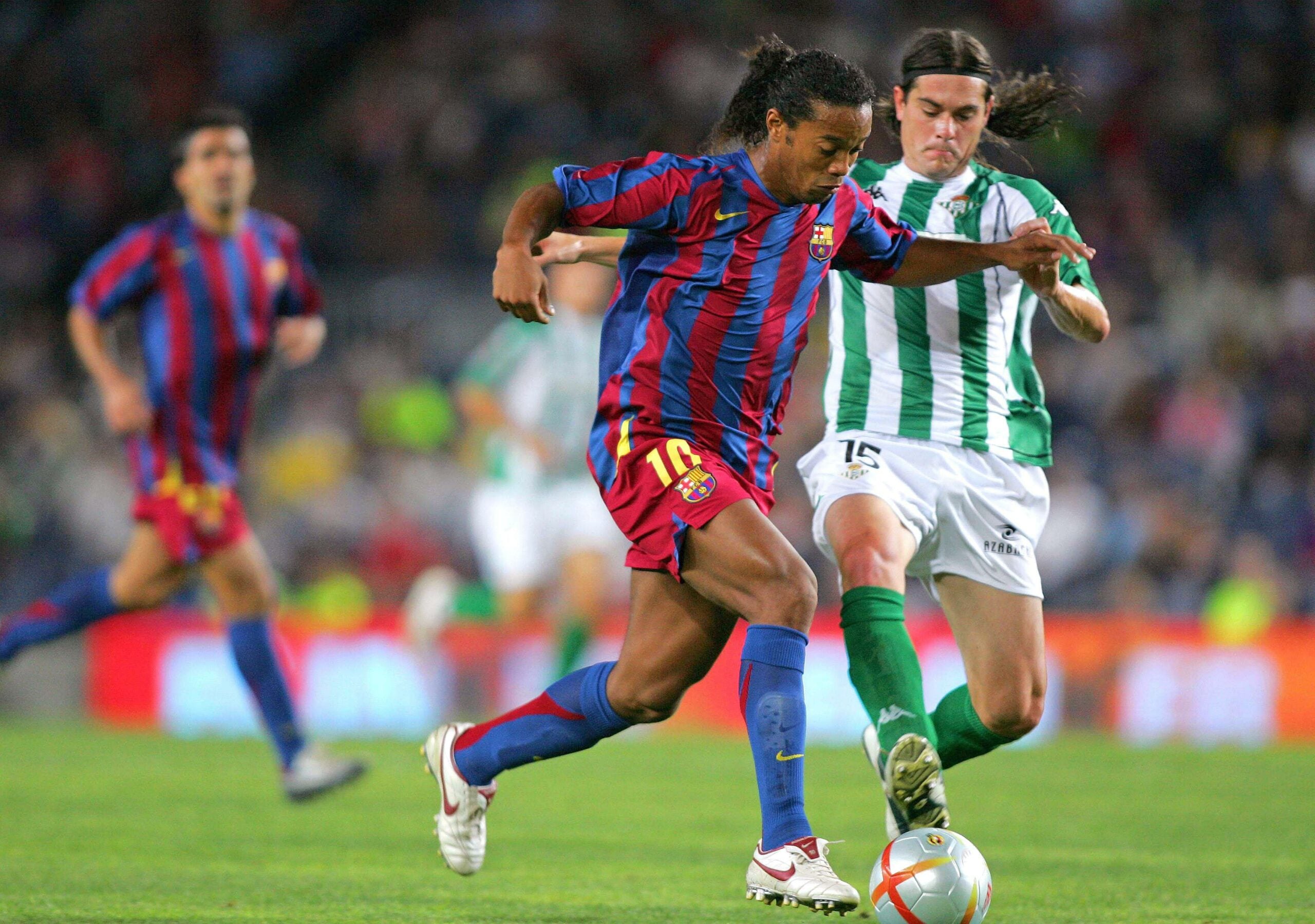 Ronaldinho do Barcelona driblando um jogador do Betis Sevilha durante uma partida da Liga Espanhola em 13 de agosto de 2005.