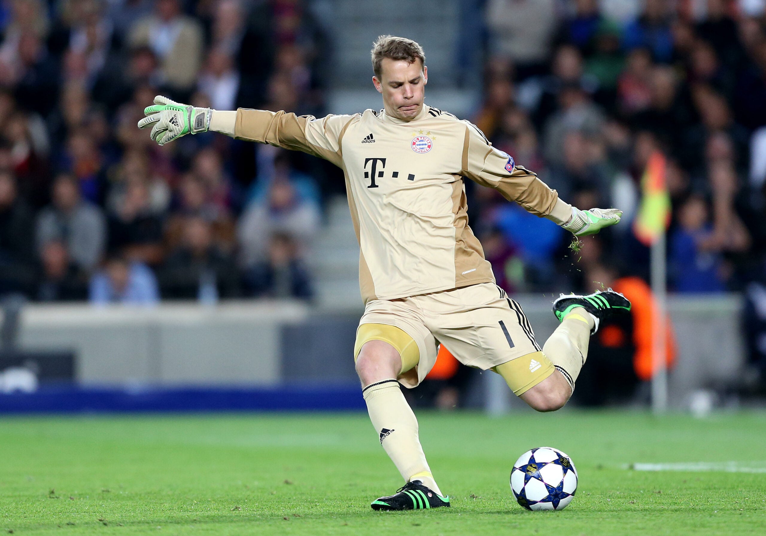 Manuel Neuer, goleiro do Bayern de Munique, chuta a bola durante uma partida, usando uniforme dourado e luvas verdes.