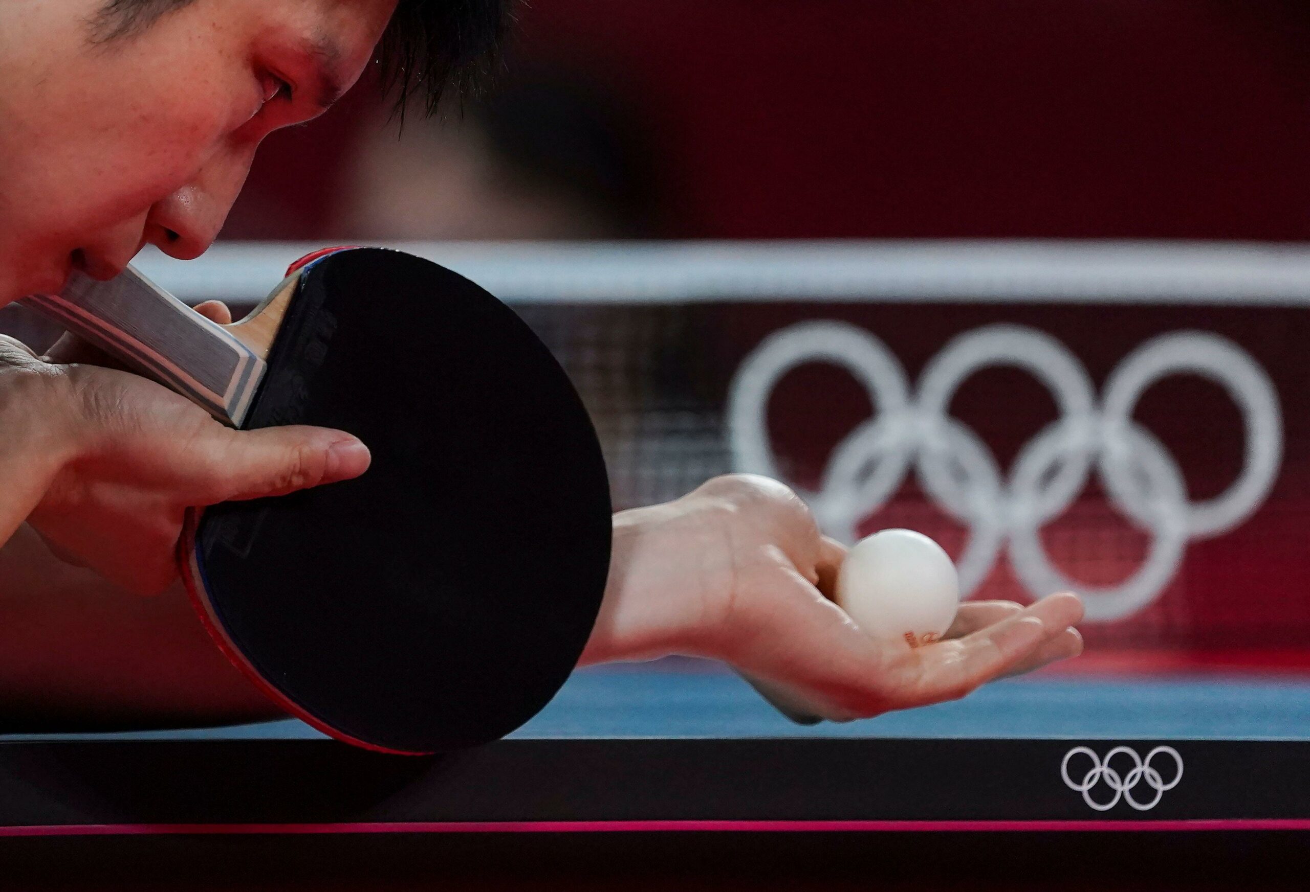 Jogador da China segurando bola para iniciar tênis de mesa