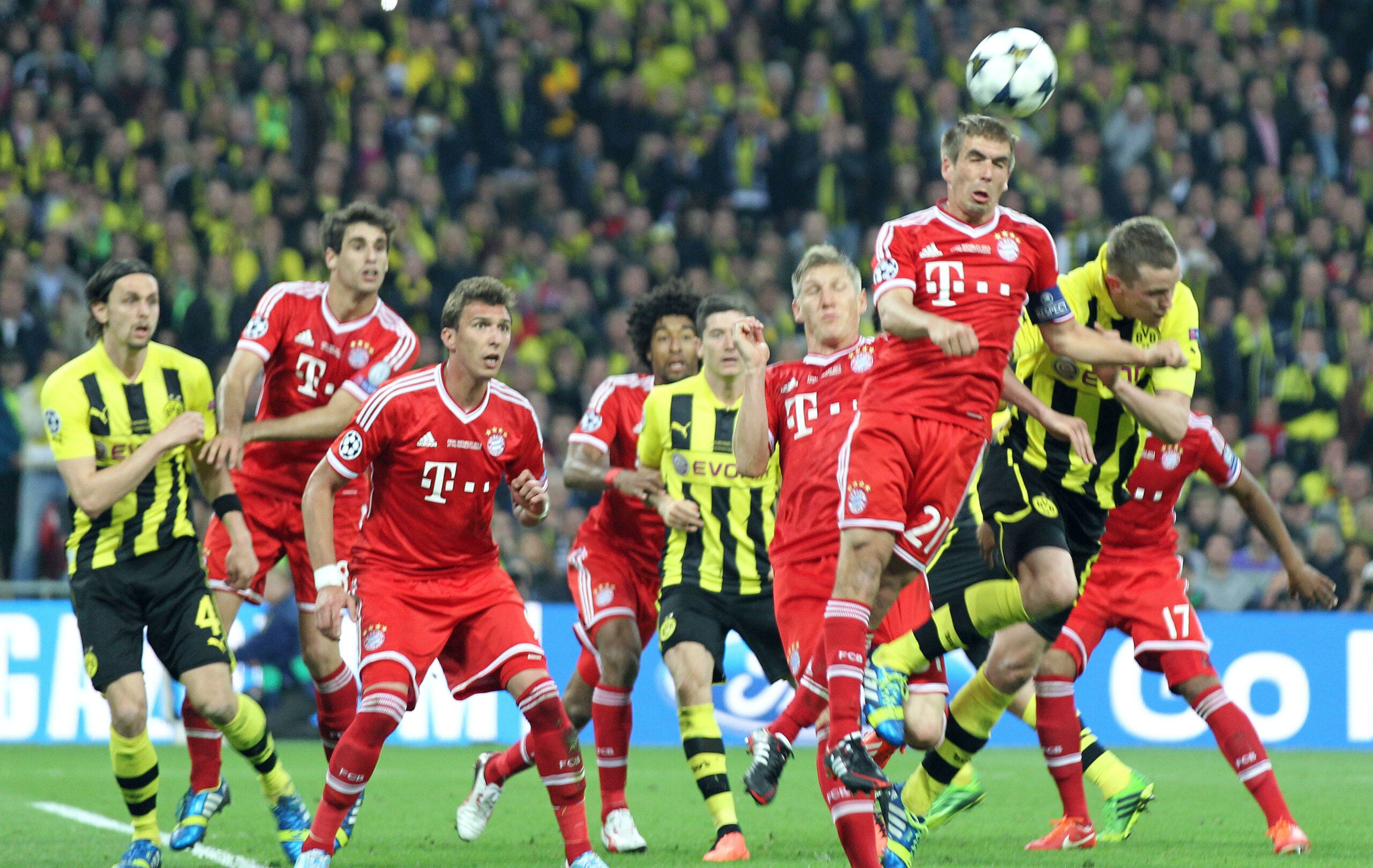 Jogadores do Bayern de Munique e Borussia Dortmund disputam intensamente a bola aérea durante uma partida.